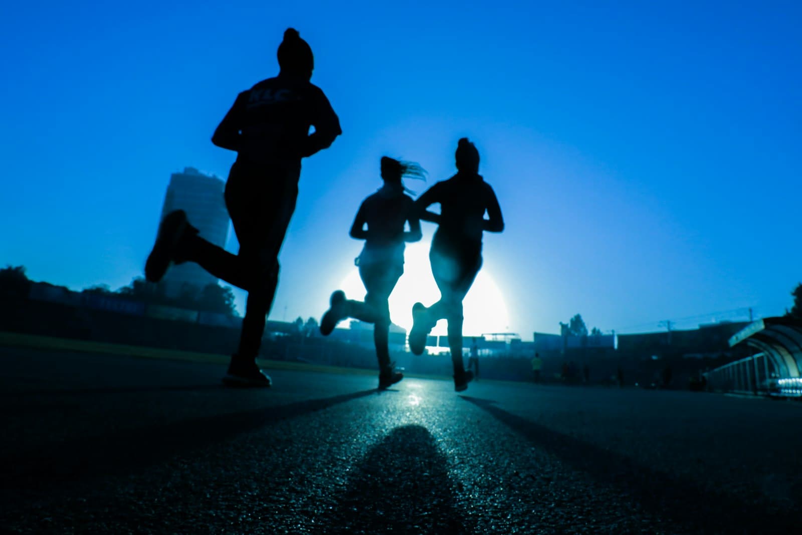 Trois coureuses de dos sur une route, en silhouette