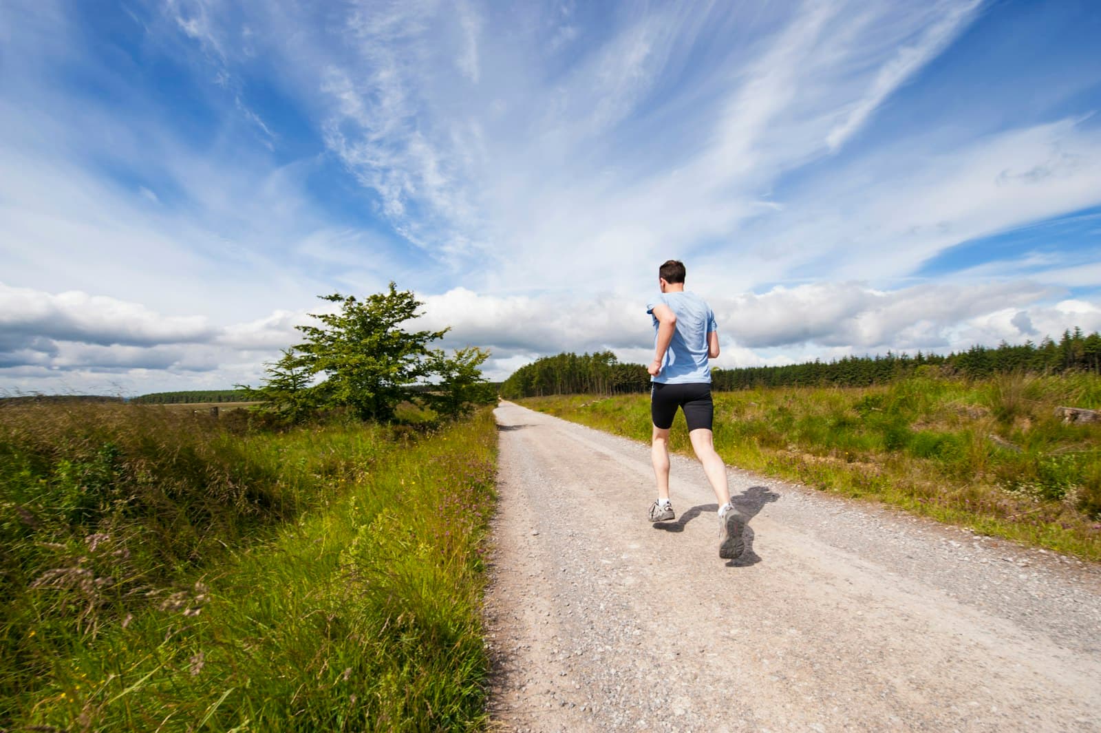 Un homme qui court sur une route bordee d'herbe